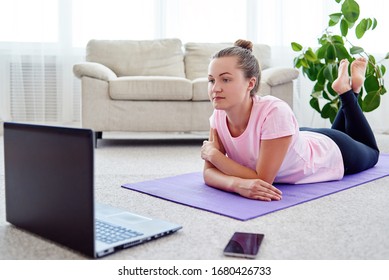 Beautiful young woman doing exercise on floor at home, online training on laptop computer, copy space. Full length portrait. Yoga, pilates, working out exercising - Shutterstock ID 1680426733
