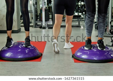 Beautiful young woman doing fitness in the gym. Girl uses fitball exercise, expander, hemisphere