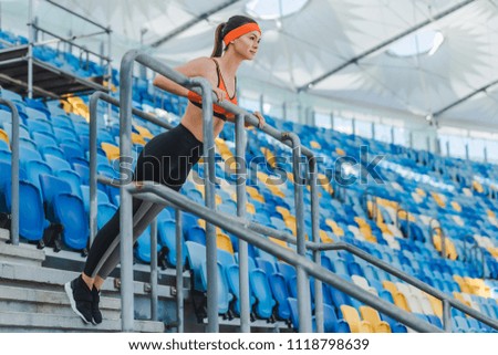 beautiful young woman doing push ups on tribunes at sports stadium