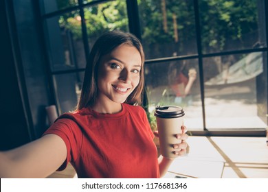 Beautiful Young Woman Doing Selfie On The Front Camera Of Her Smartphone And Holding A Paper Cup With A Drink