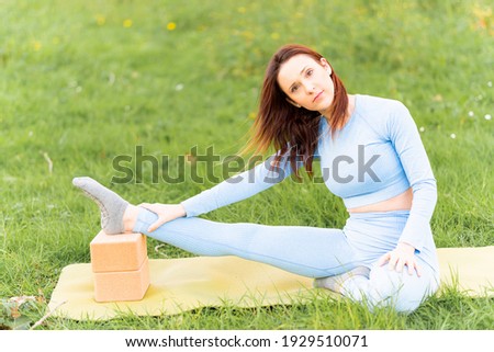 Beautiful young woman doing yoga in a park at sunset in spring or summer. yoga instructor concept. yoga class. commercial yoga. copy space