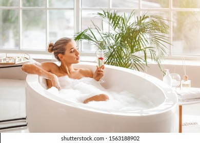 Beautiful young woman drinking champagne in bathroom - Shutterstock ID 1563188902