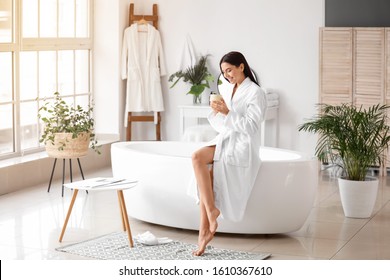 Beautiful young woman drinking coffee in bathroom - Powered by Shutterstock