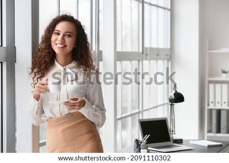 Beautiful young woman drinking coffee in office