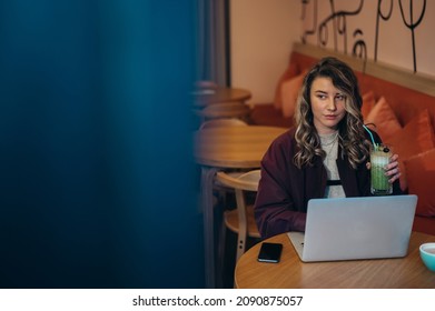 Beautiful Young Woman Drinking Matcha Latte Coffee And Working On Her Laptop In A Cafe