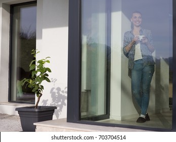 beautiful young woman drinking morning coffee by the window in her home - Shutterstock ID 703704514