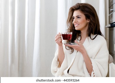 beautiful young woman drinking tea at home in the kitchen - Powered by Shutterstock