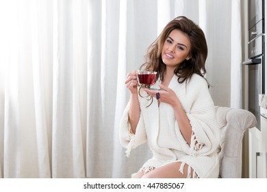 beautiful young woman drinking tea at home in the kitchen - Powered by Shutterstock