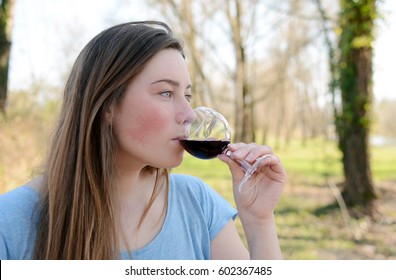 Beautiful Young Woman Drinking Wine In The Park. 