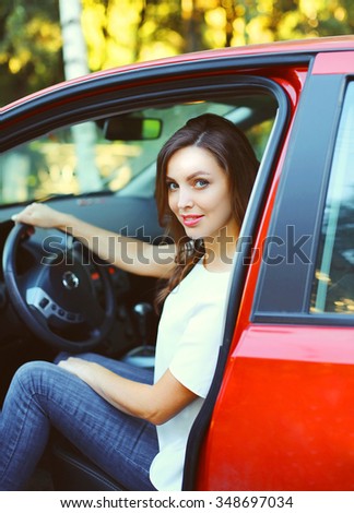 Beautiful young woman driver behind the wheel red car