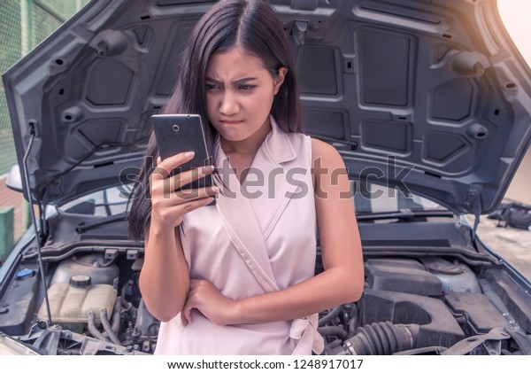 Beautiful young  woman  driver worry calls with\
smartphone for instruction during insurance agent review the\
dammage of the car after accident\

