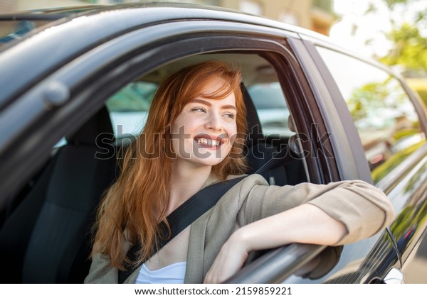 Beautiful young woman\
driving her new car at sunset. Woman in car. Close up portrait of\
pleasant looking female with glad positive expression, woman in\
casual wear driving a\
car