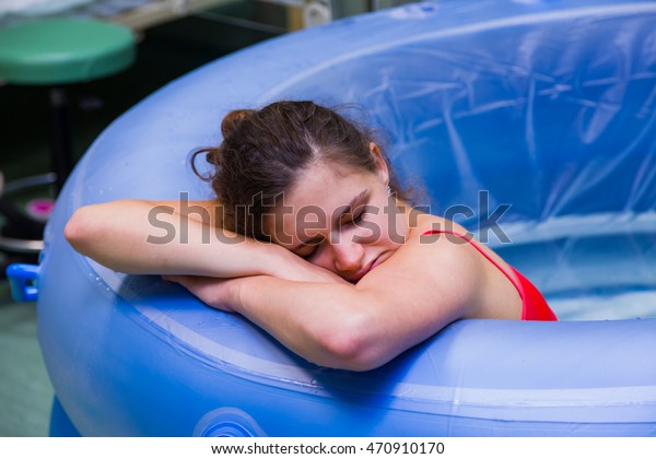 Beautiful young woman during labour, having\
painful cramps, giving birth in\
water.