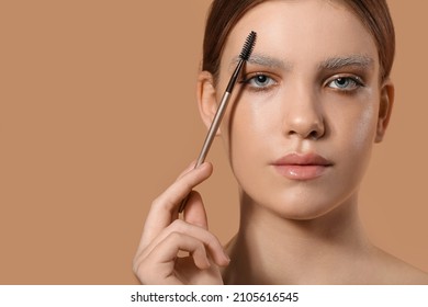 Beautiful young woman with dyed eyebrows and brush on color background - Shutterstock ID 2105616545