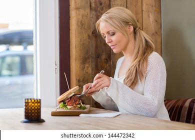 Beautiful Young Woman Eating Burger At Restaurant