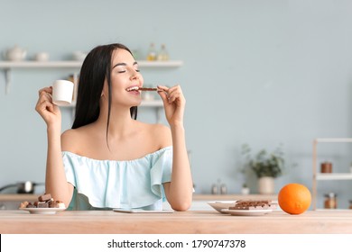 Beautiful Young Woman Eating Chocolate In Kitchen