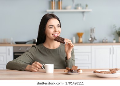 Beautiful Young Woman Eating Chocolate In Kitchen