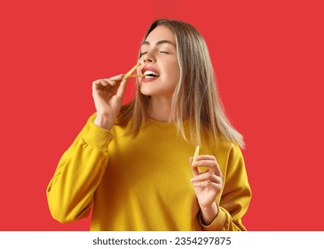 Beautiful young woman eating french fries on red background - Powered by Shutterstock