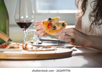 Beautiful Young Woman Eating Homemade Pizza And Drinking Red Wine At Home