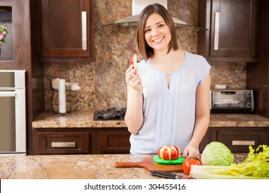 Beautiful Young Woman Eating Some Apple Slices After Using A Slicer In The Kitchen