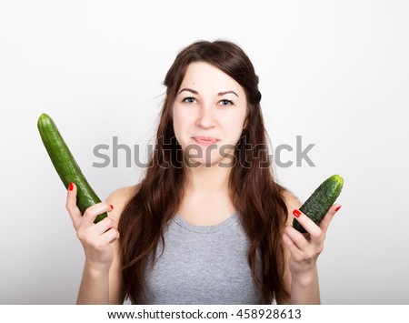 beautiful young woman eating an vegetables. selection, small or big cucumber. healthy food - strong teeth concept.