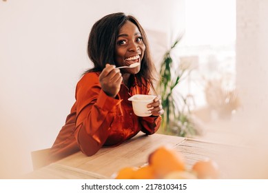 Beautiful Young Woman Eating Yogurt In The Kitchen In The Morning. Healthy Food. Close Up. Portrait Shot