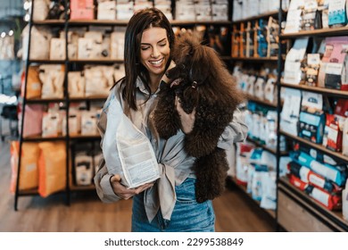 Beautiful young woman enjoying in modern pet shop together with her adorable brown toy poodle.  - Powered by Shutterstock