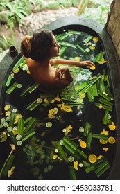 Beautiful Young Woman Enjoying In Outdoor Spa. Luxury Stone Bath Tub With Jungle View. Natural Organic Tropical Ingredients In The Water: Ginger, Lime, Orange And Sea Salt. Beauty Treatment Concept.