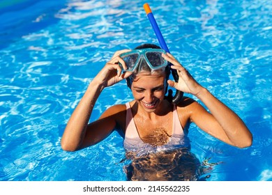 Beautiful young woman enjoying while on summer vacation putting on snorkel mask, having fun snorkeling in the swimming pool