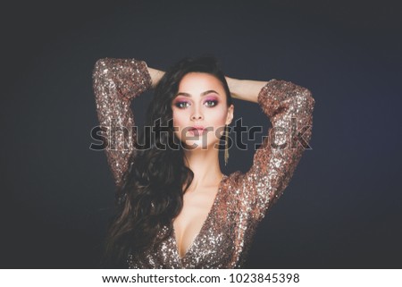 Beautiful young woman in evening dress on black background.