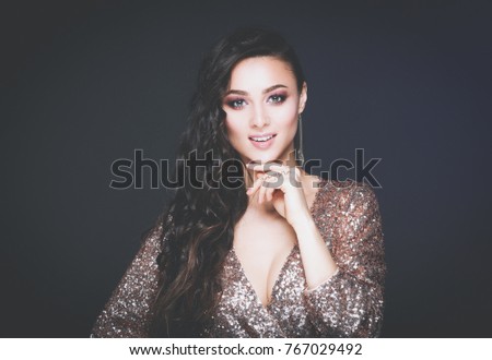 Beautiful young woman in evening dress on black background.