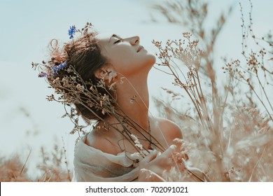beautiful young woman with eyes closed on a field at sunset