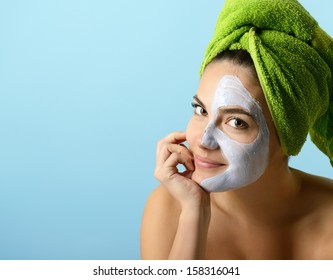 Beautiful young woman with facial mask, beauty treatment over blue