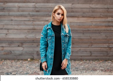 Beautiful Young Woman In Fashionable Denim Jacket Posing Near Vintage Wooden Wall