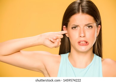 Beautiful young woman with with finger in her ear on yellow background