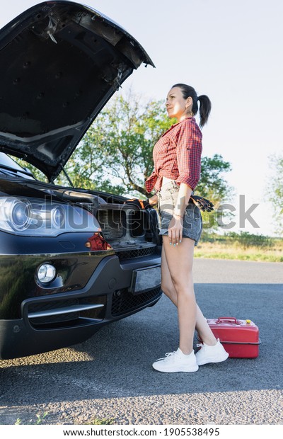 Beautiful young woman
fixing the car on the roadside . Girl in shirt and jeans ready to
repairing her car. woman mechanic . broken car on the road and
woman waiting for
help