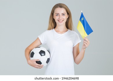 Beautiful young woman with the flag of Ukraine and a soccer ball in her hands, looks at the camera, is isolated on a gray background. - Powered by Shutterstock