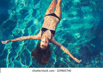 Beautiful Young Woman Floating In Pool Relaxing