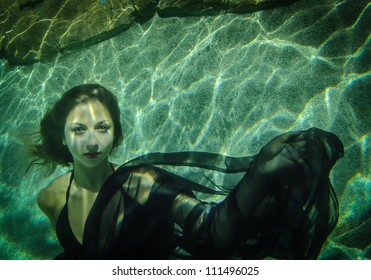 Beautiful young woman floating underwater in a black dress - Powered by Shutterstock