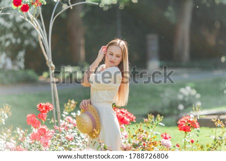 Beautiful young woman in a flower garden. Young beautiful woman portrait. Roses.