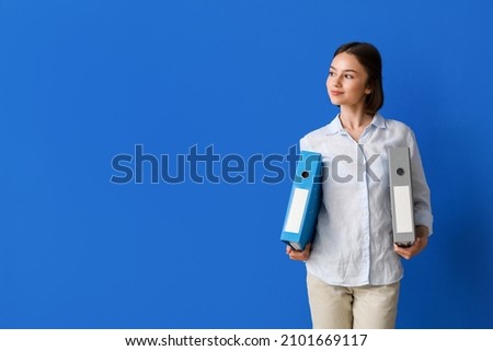 Beautiful young woman with folders on color background