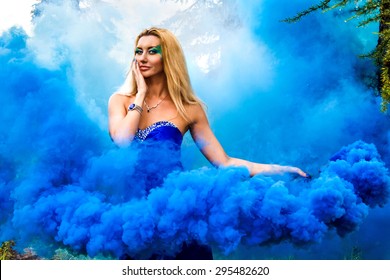 Beautiful Young Woman In Forest In Cloud Of A Bright Blue Smoke