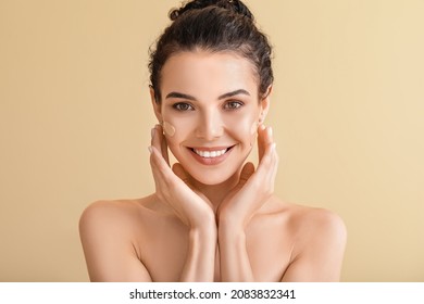 Beautiful young woman with foundation on her face against color background