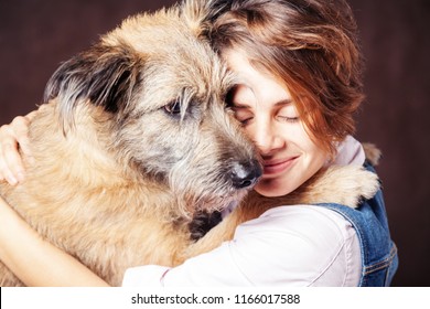 Beautiful young woman with a funny shaggy dog on a dark background. Love, care, friendship - Powered by Shutterstock