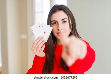 Beautiful young woman gambling playing poker pointing with finger to the camera and to you, hand sign, positive and confident gesture from the front