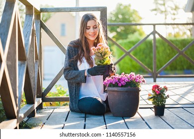 Beautiful young woman gardening in pots on the terrace,at home, with working gloves. Gardening as hobby and leisure concept.