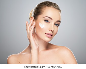 Beautiful young woman gets cream in the face. Skin care concept. Stunning caucasian woman with perfect health clean skin. Portrait of an Attractive girl  with blue eyes, closeup.  - Shutterstock ID 1176547852