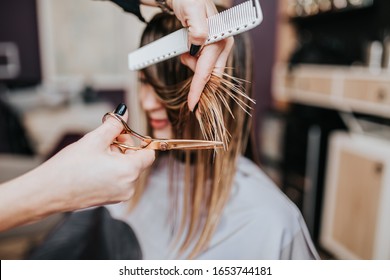 Beautiful young woman getting her haircut by a hairstylist at a beauty salon.