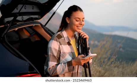 Beautiful, young woman getting ready for hiking on the mountain and using her smartphone while sitting on the car trunk	
 - Powered by Shutterstock