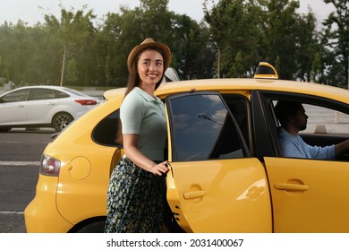 Beautiful Young Woman Getting In Taxi On City Street